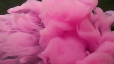 Duman üfleme. Mürekkep atışı. Pembe kıvrım pigmenti suyun altında çözünür. Siyah arkaplan üzerine sisli sıvı parlak sprey. Odaklanamayan soyut akış.