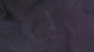 Kara buhar. Kozmik akış. Violet ışıldayan pigment spirali suda çözünür. Parıldayan soyut mürekkep karışımı gece rengi bulanık arkaplan.