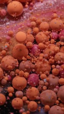 Dikey video. Mistik akış. Acryl kabarcığı. Turuncu pembe kıvrımlı köpüklü yağ emülsiyon dokusu. Suyun soyut duman arka planında renkli mürekkep damlaları.