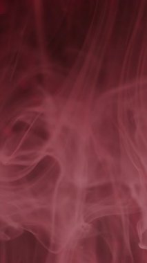 Dikey video. Duman su sıçratıyor. Bulanık boya sıvısı. Odaklanmamış pembe renkli ışıltı, soyut koyu arkaplan üzerindeki buhar bulutu deseni sis dalgası..