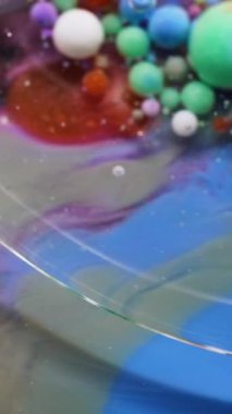 Dikey video. Sanat sıvısı. Kabarcık boyası. Şeffaf yağ çemberi mürekkep renkli damlalar mermer üzerinde yüzen köpük titreyen su soyut arka plan yüzeyi.