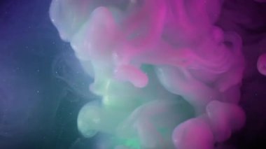 Duman akışı. Neon mürekkebi. Mor yeşil dumanlı patlama. Parlayan sıvıyla harmanlanmış renk. Siyah kozmik soyut odaklanmış arkaplan.