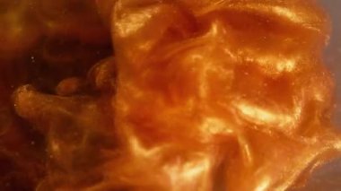 Parlak mürekkep. Buhar sanatı. Odaklanmamış altın turuncu renk. Sıvı, pırıl pırıl parlayan arka planda dönen sis..