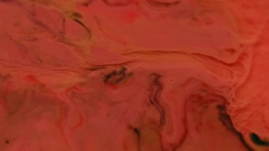 Dalgalanma lekeleri. Sıvı arka plan. Odaklanmamış turuncu pembe akrilik boya parlak su dokusu sanatın koyu siyah soyutlaması üzerinde akıyor..