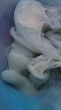 Dikey video. Karışık renk. Akan boya. Soyut sanat arka planında çözünmüş mavi mor duman kimyasal ıslak buhar suyu sıvısı.