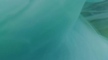 Boya fırıldağı. Dalga sisi. Akışkan mürekkep fantazisi renkli su altı girdabı. Mavi yeşil soyut kimya sıçraması odaklanmış arkaplan.