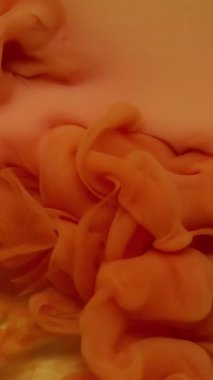 Dikey video. Mürekkep su sıçratır. Akışkan bulut. Odaklanmamış turuncu renkli kimyasal karışım sıvısı soyut ıslak arka planda yayılıyor..