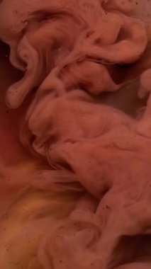 Dikey video. Parçacık arkaplanı. Soyut boya. Odaklanmamış pembe bronz mürekkep. Su parlatıcısı dumanında. Siyah sanatta pigmente sıçramış..
