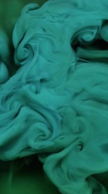 Dikey video. Sıvı pigmenti. Duman mürekkebi. Odaklanamayan mavi renkli su kıvrımlı akrilik karışım soyut koyu siyah arkaplan üzerinde akıyor.