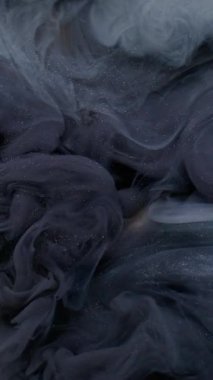 Dikey video. Parıldayan parçacıklar. Mürekkep akışı. Beyaz soyut arkaplanda uçuşan koyu mavi renkli sıvı akrilik pigment su dokusu.