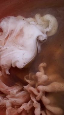 Dikey video. Sis dokusu. Mürekkep suyu. Bulanık pembe beyaz renkli duman dalgası soyut koyu siyah arkaplanda yayılan parlak parçacıklar..