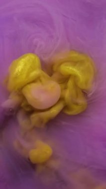 Dikey video. Harman boyası. Akrilik rengi. Su parçacıklarının içine dökülen sarı mor bulutlar soyut arkaplana yayılıyor..