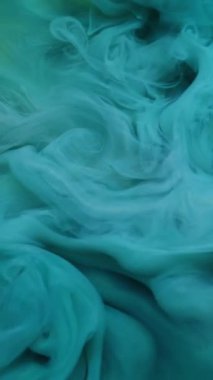 Dikey video. Sis rengi. Sıvı mürekkep. Odaklanamayan mavi cyan duman dokusu kimyasal sıçrama su girdabı soyut arkaplan üzerinde yüzüyor.