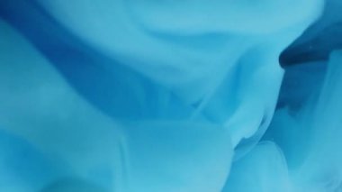 Sanat dumanı. Mürekkep atışı. Mavi kıvrım pigmenti suyun altında çözülür. Siyah arkaplan üzerinde sisli sıvı parlak deniz mavisi püskürtüsü soyut odaklanmış akış.