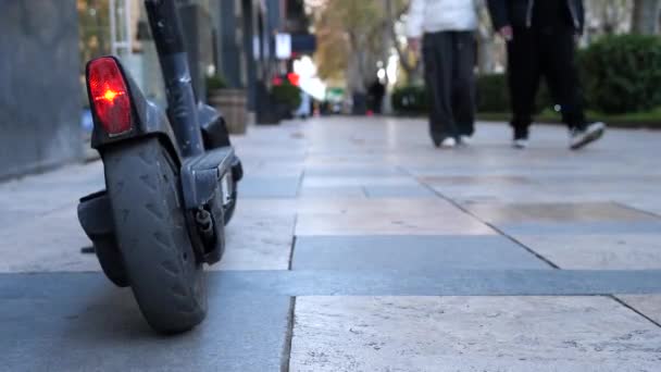 电单车停在街上的人行道上 红灯亮着 车胎磨损 停放在路面上的黑色电单车的地面射击 — 图库视频影像