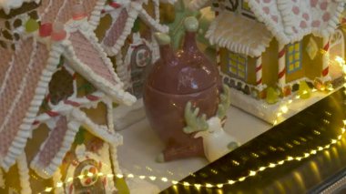 Minyatür Noel evleri, heykelcikler ve dekorasyonlar, dükkan vitrininin arkasındaki ışıklarla aydınlatılmış. Mağaza vitrininde sihirli Noel atmosferik dekorasyonlarının yüksek açılı çekimi.