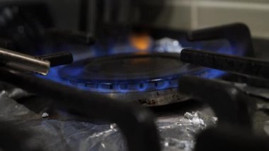 Gaz sobasını gaz çakmağını kullanarak ısıtırken yakın çekim yap. Birinin, gümüş folyoyla kaplanmış kirli sobayla gaz ocağını ısıtırken elde çekilmiş bir fotoğrafı..