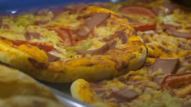 Fast food pastanesinde ucuz pizzalar. Gümüş renkli metal tepsilerde dönen pizzalar..