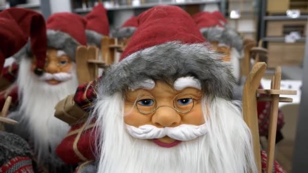 圣诞节期间 许多圣诞老人的玩具娃娃成排地站在商店的内部 在购物中心的货架上 挂着红礼盒和木制滑雪板的白胡子笑脸圣诞老人的潘宁照片 — 图库视频影像