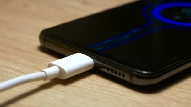 Usb充电电缆连接 并将电力传输到智能手机 在屏幕上快速充电蓝色流体颗粒动画 黑色现代智能手机 充电时躺在木制桌子上 — 图库视频影像