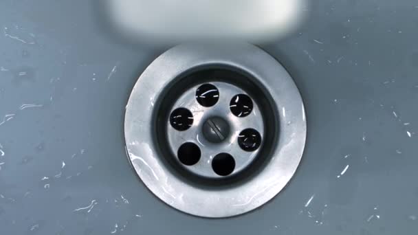 클로즈업 비디오는 화장실 싱크대에서 스테인레스 배수구 아래로 빠르게 흐르는 깨끗한 — 비디오