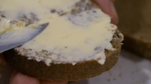 用小刀在白盘上的一片黑面包上平稳地撒满黄油 详细介绍了一个简单的日常厨房任务 一个极端的特写镜头 — 图库视频影像