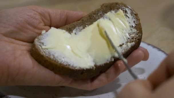 Ruce Hladce Roztírající Máslo Nožem Plátek Tmavého Chleba Bílém Talíři — Stock video