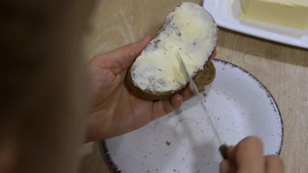 Kobieta Płynnie Rozkłada Masło Nożem Plasterku Ciemnego Chleba Białym Talerzu — Wideo stockowe