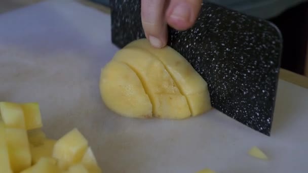 白种人将土豆切成小块 白桌上放着一把大厨小刀 在自家厨房的环境中与家人共进晚餐 这是一个近距离视频 — 图库视频影像