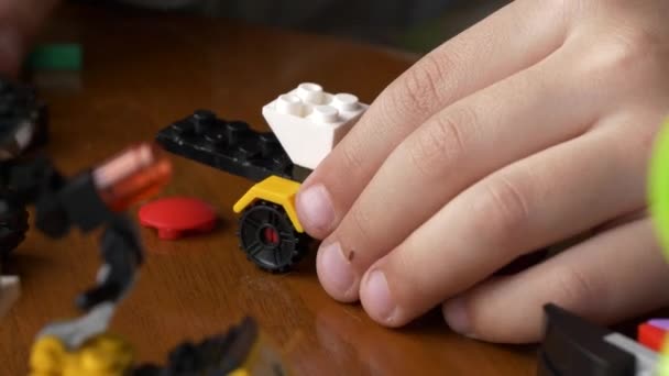 在一张木制桌子上 孩子们手忙脚乱地组装着一辆五颜六色的玩具车的特写镜头 — 图库视频影像