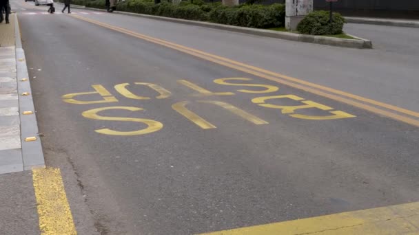 Piesi Przejeżdżający Przez Magistralę Napisem Bus Stop Wydrukowanym Asfaltowej Drodze — Wideo stockowe