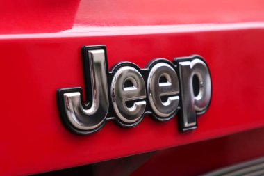 Dışarıdaki Jeep aracının canlı kırmızı arka planında parlak bir Jeep ambleminin detaylı bir görüntüsü. Tiflis, Gürcistan - 23 Mart 2024.