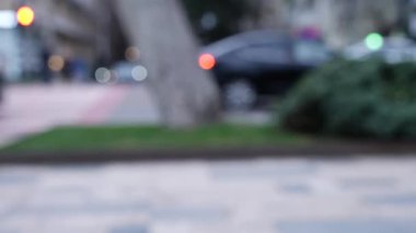 Gece çöktüğünde şehir caddesinde yayaların ve araçların bulanık hareketi.