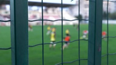 Sahada koşan oyuncularla yapılan rugby antrenmanı, stadyum çitlerinin dışından gündüz gözüyle görülebiliyor..