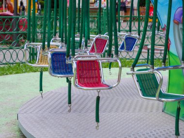 Güneşli bir günde lunaparkta sallanan renkli atlı sandalyeler..