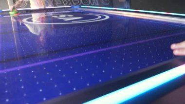 Çocuklar hava hokeyi masası oyunu oynuyorlar, ve diske raketlerle vuruyorlar, yakın çekim..