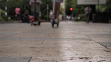 Bir grup çocuk öğleden sonraları hareketli bir şehir yolunda scooterlarını sürmekten zevk alır..