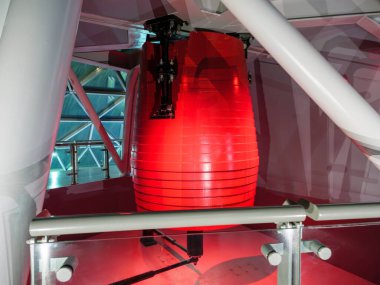 Red tuned mass damper pendulum is installed on the top floor of a high-rise structure, designed to reduce the buildings oscillations during high winds or seismic activity and ensure stability. clipart