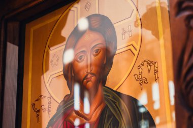 Camın arkasındaki yumuşak ışık yansımalarıyla aydınlatılan altın bir halkayla büyüleyici İsa 'nın yüz ikonu, yansıtıldığı çevreye ruhani bir hava katıyor..