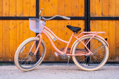Önünde sepet olan büyüleyici bir klasik bisiklet ahşap bir çitin karşısında duruyor ve nostalji hissi uyandırıyor. Sepetli Retro tarzı kadınsı bisiklet.