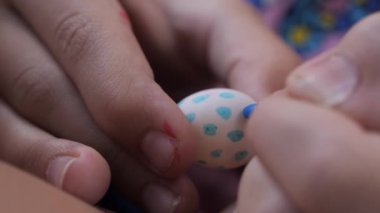 Çocuk elleri titizlikle küçük bir paskalya yumurtasını dekore eder, mavi işaretli desenler çizer, aşırı yakın çekim..