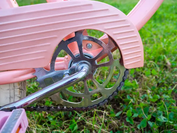 stock image Vintage pink bicycle chainring with the silver crank on a green grass background.