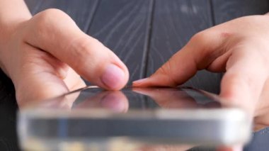 Bir kadın akıllı bir telefon tutuyor ve tek parmakla kaydırıyor, yakın çekim..