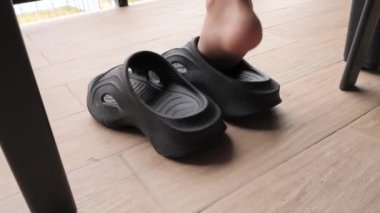 Bir insan giymeye hazır şık siyah platform sandaletleri alır. Evde rahatlamak için lastik sandalet ayakkabısı seçiyorum..