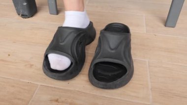 Bir insan giymeye hazır şık siyah platform sandaletleri alır. Evde rahatlamak için lastik sandalet ayakkabısı seçiyorum..