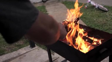 Bir el maharetle odun ve odun toplar ve şömineyi tutuşturur. Bir yaz öğleden sonra ızgarada arka bahçedeki barbekü ateşini hazırlamak, yavaş çekim görüntüleri..