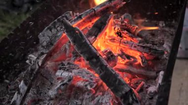 Sıcak közler ızgarayı doldurup sıcak bir atmosfer yaratıyor. Arka bahçedeki ızgarada parlayan ve yanan odun közleri..