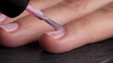 Kadınların eli, hassas ve özenle pembe tırnak cilası sürüyordu. Tırnaklar manikür işlemi.
