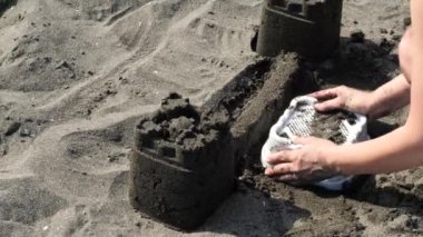 Yaz günü kumsalda kumdan kale yapan bir adam. Gündüz kumsalda kumdan kale yapmak.