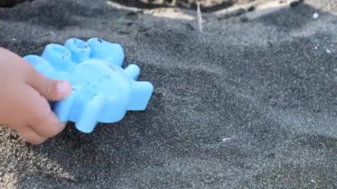 Çocuk elleri kumsaldaki yengeç şeklindeki kumu şekillendirir.. 